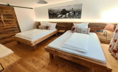 two beds in a room with wooden floors at Landhaus im Allgäu in Halblech