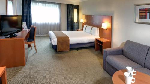 um quarto de hotel com uma cama, um sofá e uma televisão em Holiday Inn Maidstone-Sevenoaks, an IHG Hotel em Maidstone