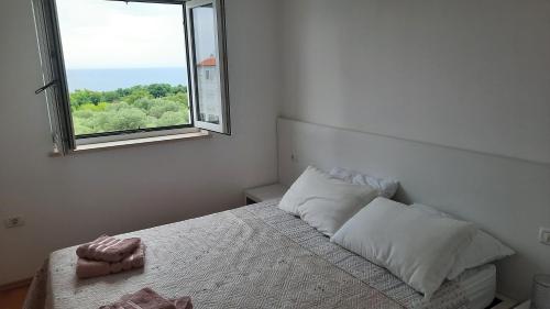 a white bedroom with a bed with a window at Apartma Coccolo in Zambratija