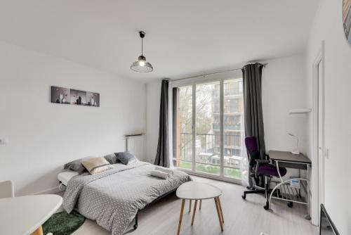 a bedroom with a bed and a desk and a window at Budget apart with balcony near Paris in Bondy