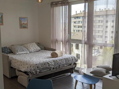 une chambre avec un lit et une grande fenêtre dans l'établissement Cocon Annécien entre lac et montagne classé 1 étoile, à Annecy