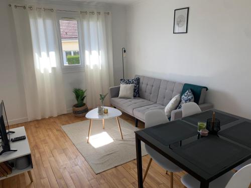 a living room with a couch and a table at Grand Parking gratuit, De 1 à 4 personnes, Tout équipé, Netflix, Amazon Prime Gratuits et Illimités, Matelas Emma, Lave Linge, Vue sur la Vallée, RDC in Pont-Hébert