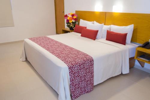 a bedroom with a large white bed with red pillows at Hotel Klimt in Xalapa