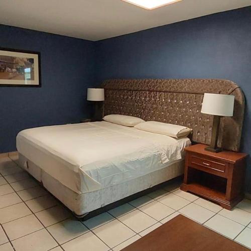 a bedroom with a large bed and a blue wall at Hotel el Cortes in Aguascalientes