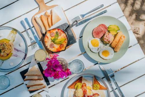 a table with plates of breakfast foods on it at Hotel Checkin El Cortecito Beach in Punta Cana