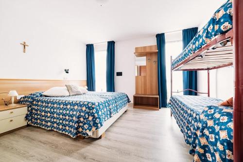 two beds in a bedroom with blue curtains at Hotel Rosmary in Lido di Jesolo