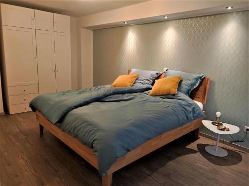 a bedroom with a bed with blue sheets and orange pillows at Ferienwohnung Im Stiffje in Schalkenmehren