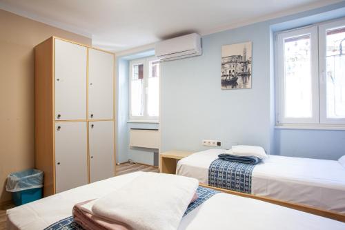 a room with two beds and two windows at Hostel Adriatic Piran in Piran