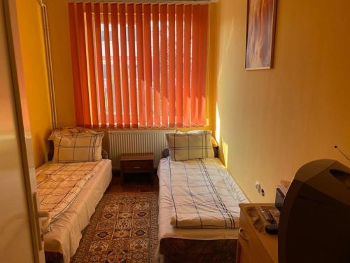 2 camas en una habitación pequeña con ventana en Villa Ani Hajduszoboszlo, en Hajdúszoboszló