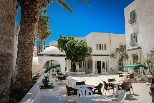 a patio with tables and chairs and a building at Emira Hotel in Hammamet