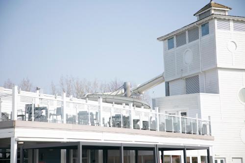 a white building with a balcony with chairs on it at 51 Lytchett Bay View, 3 bed, Rockley Park Poole in Poole