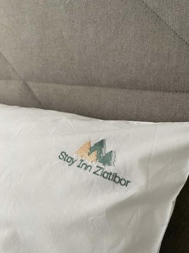 a bed with a white pillow with a sign on it at Stay Inn Zlatibor in Zlatibor