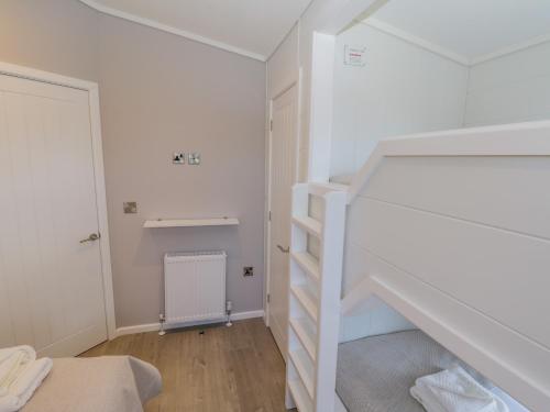a bedroom with white walls and a staircase with white shelves at No 27 The Crab Pot in Saltburn-by-the-Sea