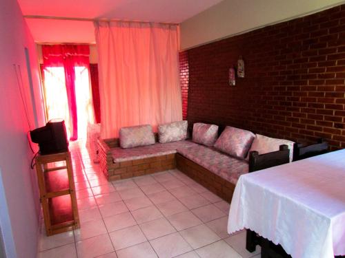 a living room with a couch and a tv at Apart-Hotel Marinas da Lagoa - 2 Praias a 4 Min - in Saquarema