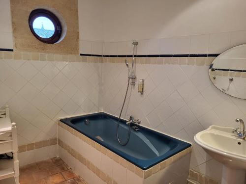 La salle de bains est pourvue d'une baignoire bleue et d'un lavabo. dans l'établissement La maison du Barry, à Collias