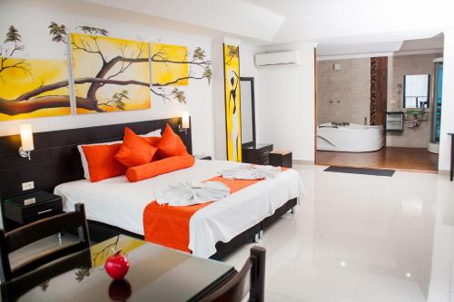 ein Schlafzimmer mit einem Bett mit orangefarbenen Kissen und einem Badezimmer in der Unterkunft Hotel Abadia in Neiva