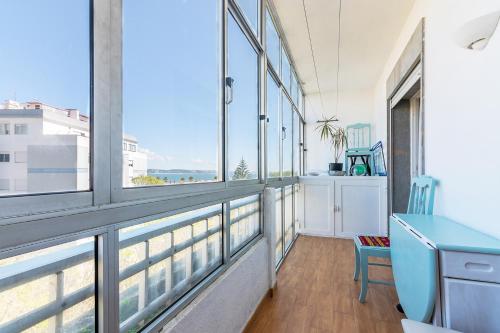 a balcony with a blue desk and windows at Paço de Arcos Apartment in Paço de Arcos