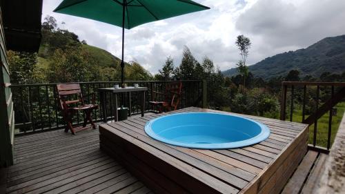 a blue pool on a wooden deck with an umbrella at Ecohotel Pinohermoso Reserva Natural in Salento