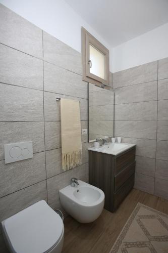 a bathroom with a white toilet and a sink at Capri 53 in Àrbatax