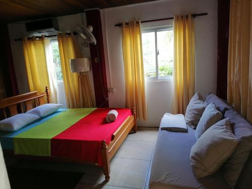 a room with a bed and a couch with a colorful blanket at Creole Cottage Homestay in Mahe