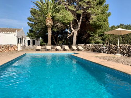 una piscina azul con sombrilla y árboles en Islanders Menorca Country Club, en Son Carrio