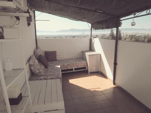 a balcony with a couch and a chair on a roof at Ático Dúplex con vistas in Murcia