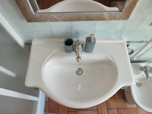 a white sink in a bathroom with two cups on it at Casa Aurora in Ravenna
