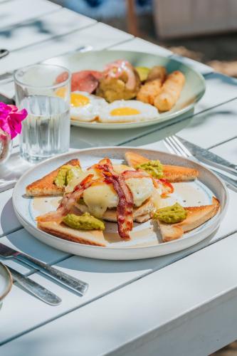 two plates of food on a table with eggs and bacon at Hotel Checkin El Cortecito Beach in Punta Cana