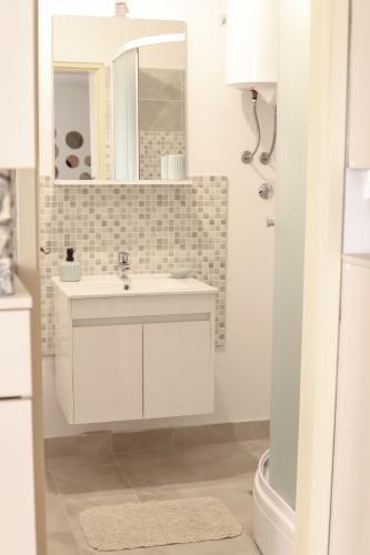 a white bathroom with a sink and a mirror at Apartman „Bernarda” in Korčula