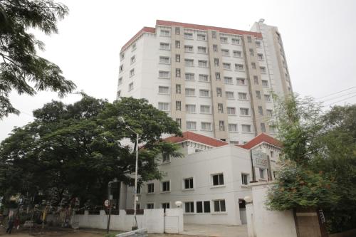 a tall white building with a tree in front of it at Rain Drops Hotel in Chennai