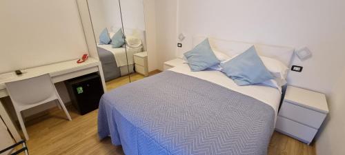 a small bedroom with a bed with blue pillows at Hotel Mare Blu -- boutique in Pineto