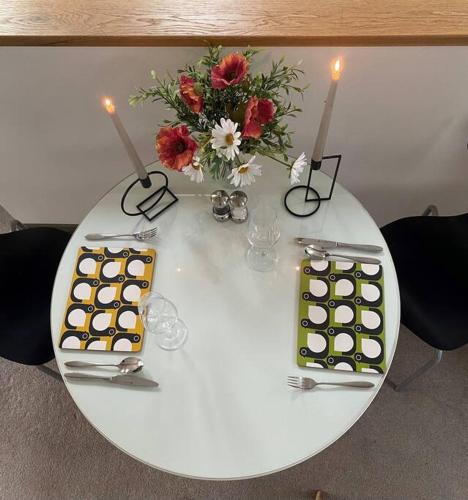 a white table with a vase of flowers and candles at Woodmill Arches - Designer Barn Conversion for Two in Lindores