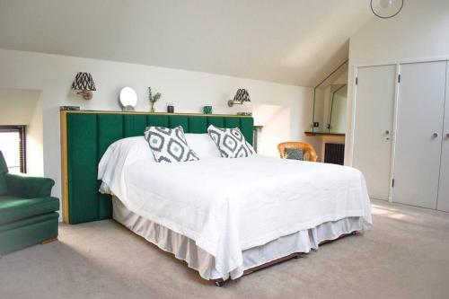 a bedroom with a large white bed with a green headboard at Woodmill Arches - Designer Barn Conversion for Two in Lindores