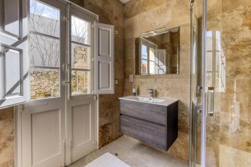 a bathroom with a sink and a shower and a mirror at Rabat Farmhouse with pool and cave in Għajn Qajjied