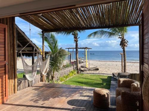a house with a porch with hammocks and the beach at Piticcaia Lodge - Casa pé na areia, Frente mar - PREÁ in Prea