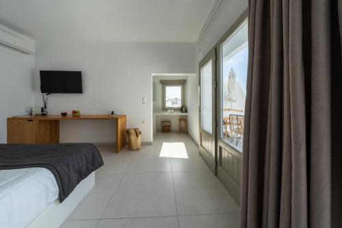 a bedroom with a bed and a large window at Smaro Studios in Firostefani