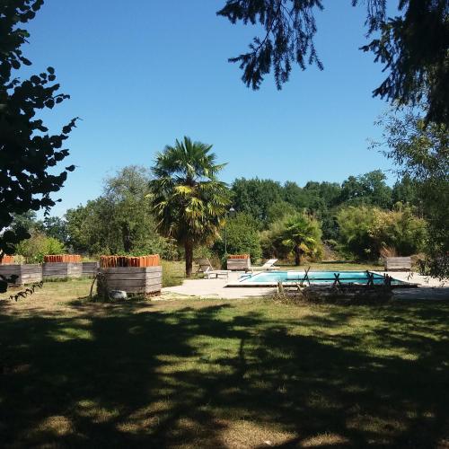 un parc avec une piscine et un arbre dans l'établissement Maison 18eme siècle, à Le Moulinaud