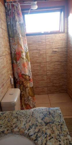 a bathroom with a toilet and a shower curtain at Chalés Portal Verde - Seja bem vindo in Carrancas