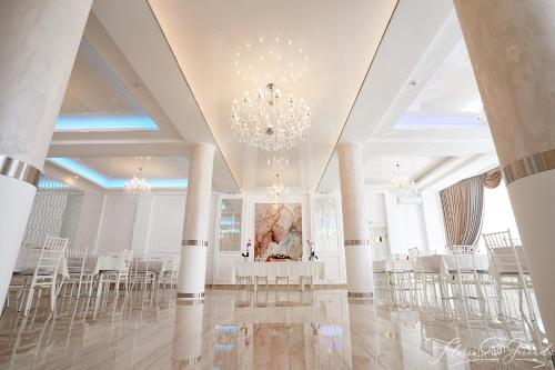 a room with white tables and chairs and a chandelier at Hotel-Restaurant Ayan Piatra Neamt in Piatra Neamţ