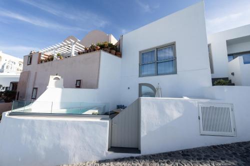 a white house with a glass door on it at Smaro Studios in Firostefani