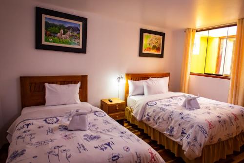 a hotel room with two beds and a window at Intitambo Hotel in Ollantaytambo