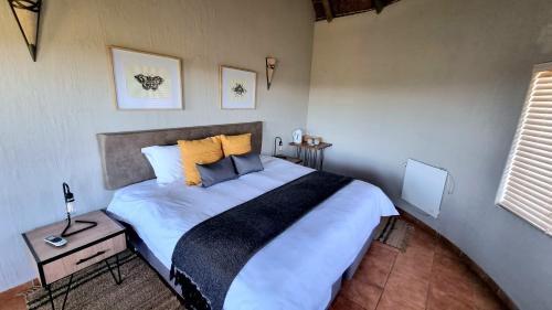 1 dormitorio con 1 cama grande con almohadas amarillas en Boabab Lodge, en Mabula