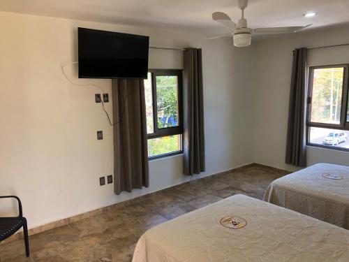 a bedroom with two beds and a flat screen tv at Hotel Conquistador in Mazatlán