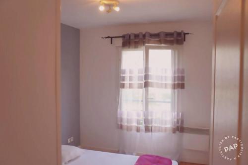 a bedroom with a window with curtains and a bed at Superbe appartement T2 de 50m2 près de Genève à Saint Julien en Genevois idéal pour couple avec 2 enfants jusqu'à 18 ans in Saint-Julien-en-Genevois
