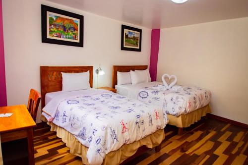 a hotel room with two beds and a table at Intitambo Hotel in Ollantaytambo