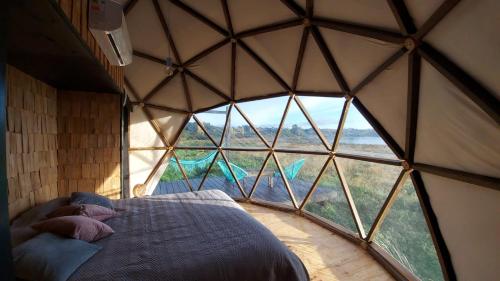a bedroom with a large window in a igloo at Glamping Domo Pullao in Castro