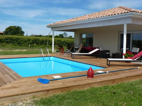 una piscina con terraza de madera y una casa en Gîte Les Vignes en Cravencères