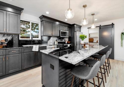 a kitchen with black cabinets and a island with bar stools at Mid Century Modern Boise-River Bungalow w/ Hot Tub in Boise
