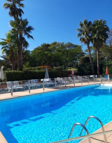 une grande piscine bleue avec chaises et parasols dans l'établissement Appartement 30 m2, piscine et parking privé, à Mouans-Sartoux