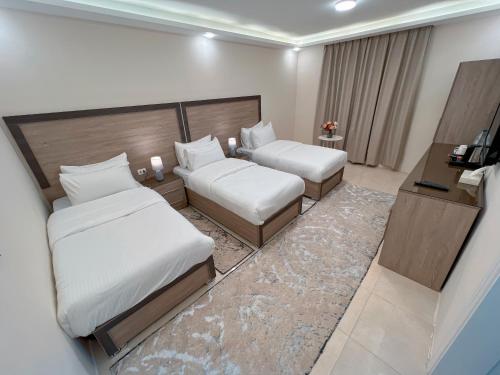 een hotelkamer met 2 bedden en een televisie bij Beit Alshabaan Inn in Wadi Musa